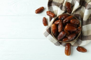 Mutfak peçetesinde beyaz ahşap arka planda kurutulmuş hurma kasesi.