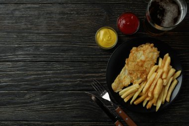 Kızarmış patates kızartması, balık ve ahşap arka planda bira ile lezzetli yemek kavramı.