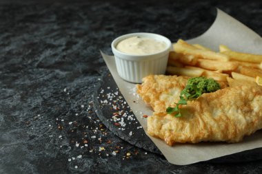 Siyah dumanlı masada kızarmış balık ve patates kızartması.