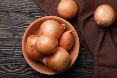 Tahta zemin üzerinde taze soğan ve mutfak havlusu olan bir kase.