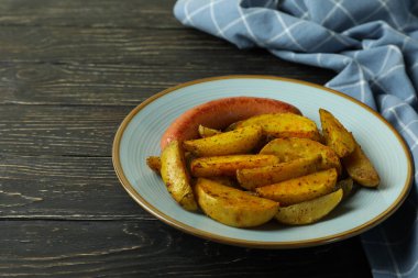 Patates kızartması, sosis ve ahşap arka planda mutfak havlusu.