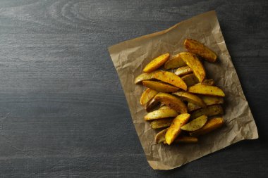 Koyu desenli arka planda patates dilimleri olan kağıt fırını.