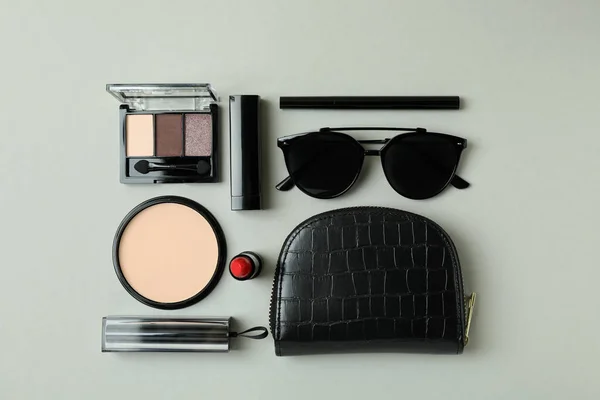 Cosmetic bag, makeup cosmetics and sunglasse on gray background