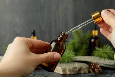 Kadın elleri çam yağıyla pipet ve şişe tutuyor.