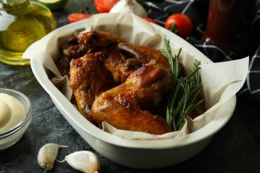 Lezzetli yemek kavramı, pişmiş tavuk kanatları ve siyah dumanlı masa.