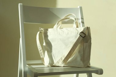 Işık duvarı arka planında şık bir çevre çantasıyla sandalye