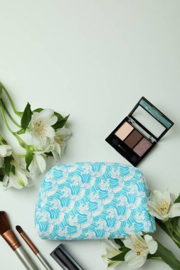 Beyaz arka planda kozmetik çanta, kozmetik ve alstromerya.