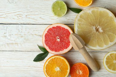 Beyaz ahşap masada farklı turunçgillerden oluşan olgun yiyecek kavramı.