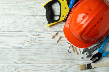 Beyaz ahşap arka planda farklı inşaat araçlarıyla İşçi Bayramı kavramı