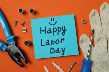 Turuncu arka planda farklı aksesuarlarla Mutlu İşçi Bayramı kavramı