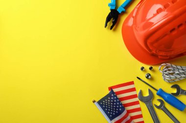 Sarı zemin üzerinde farklı aksesuarlar bulunan Mutlu İşçi Bayramı kavramı