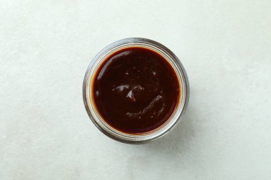 Beyaz desenli arka planda cam kavanoz barbekü sosu.