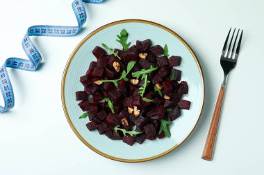 Beyaz arka planda pancar salatası, çatal ve mezura ile tabakta