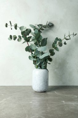 Gri desenli masa üzerinde okaliptüs dalları olan vazo