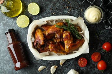 Lezzetli yemek kavramı, pişmiş tavuk kanatları ve siyah dumanlı masa.