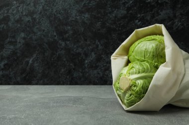 Gri masada taze yeşil lahana torbası.