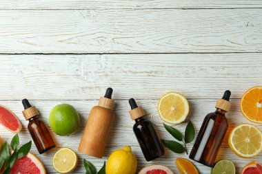 Yağlı damlalar ve beyaz ahşap arka planda farklı turunçgiller.