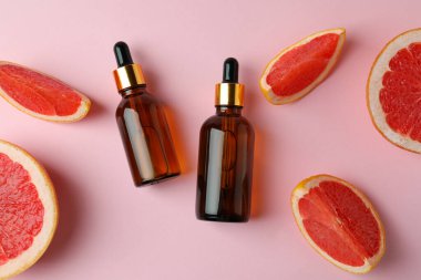 Pembe arka planda yağlı ve greyfurt dilimli damlalar.