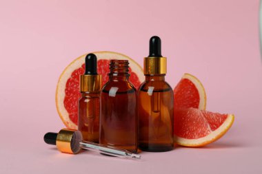 Pembe arka planda yağlı ve greyfurt dilimli damlalar.