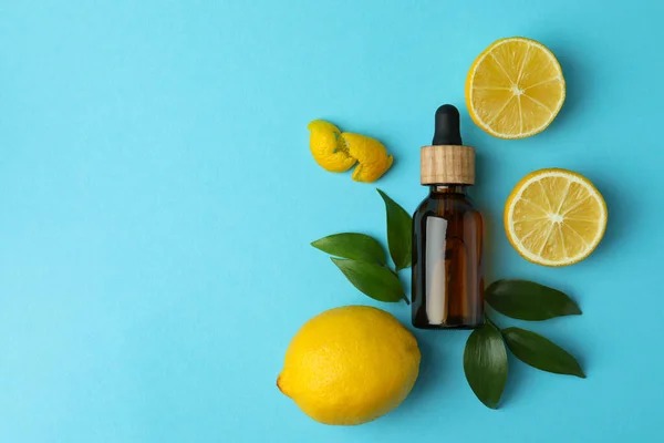 Dropper bottle with oil and lemons on blue background