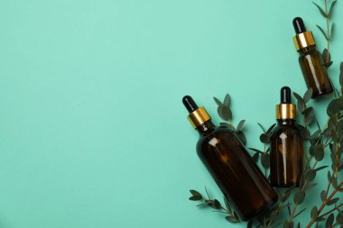 Kahverengi okaliptüs yağı şişeleri ve naneli arka planda dallar.