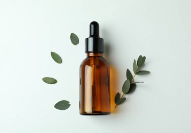 Beyaz arka planda kahverengi okaliptüs yağı ve dal şişesi