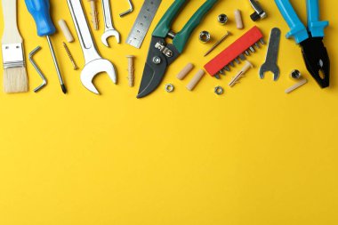 Different working tools on yellow background, space for text