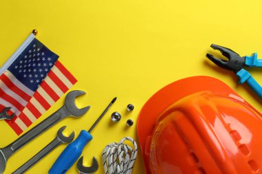 Sarı zemin üzerinde farklı aksesuarlar bulunan Mutlu İşçi Bayramı kavramı