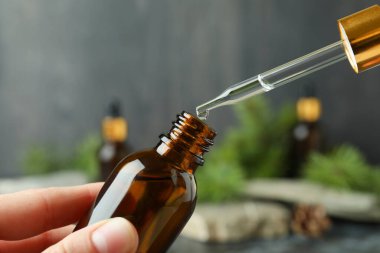 Kadın elleri çam yağıyla pipet ve şişe tutuyor.