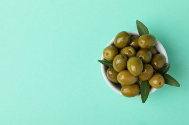 Bir kase yeşil zeytin ve nane arkaplanda yapraklar