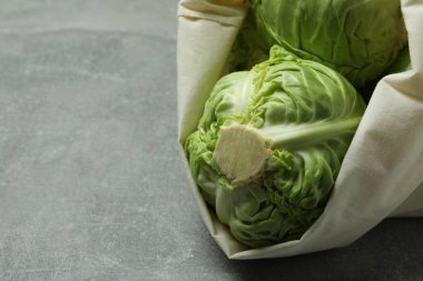 Gri masada taze yeşil lahana torbası.