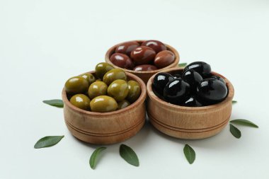 Beyaz arka planda tahtadan zeytin kaseleri ve yapraklar