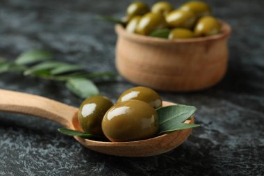 Kase dolusu zeytin ve siyah dumanlı arka planda yapraklar.