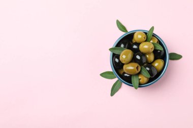 Bir kase zeytin ve pembe arka planda yapraklar