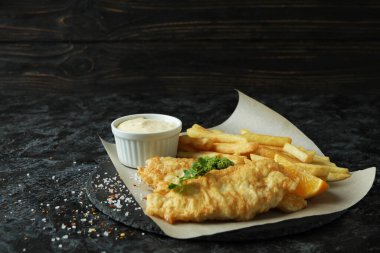 Siyah dumanlı masada kızarmış balık ve patates kızartması.