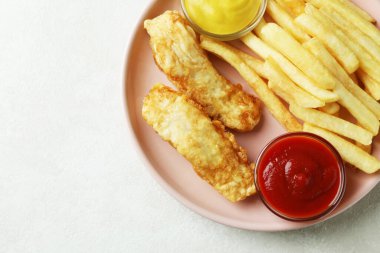 Kızarmış balık ve patates kızartması tabağı ve beyaz desenli soslar.