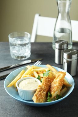 Koyu dokulu masada kızarmış balık ve patates kızartması ile lezzetli yemek kavramı.