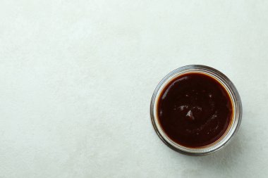 Beyaz desenli arka planda cam kavanoz barbekü sosu.