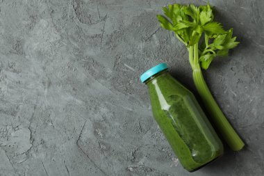 Gri arka planda bir şişe yeşil smoothie ve kereviz