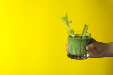 Sarı arkaplanda bir bardak smoothie var.