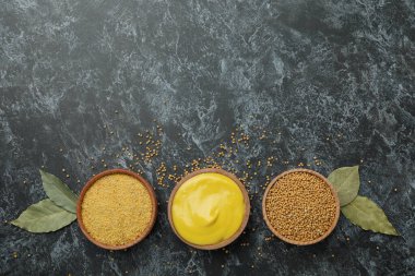 Siyah dumanlı arka planda hardal tohumu, sos ve toz dolu kaseler.