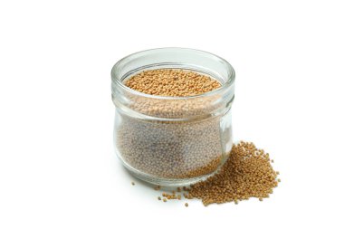 Beyaz zemin üzerinde hardal tohumları olan cam kavanoz.