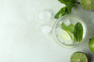 Bir bardak mojito kokteyli ve beyaz desenli masa malzemeleri.