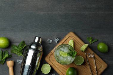 Bir bardak mojito kokteyli, koyu ahşap arka planda malzemeler ve titretici.