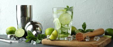 Bir bardak mojito kokteyli ve malzemelerle dolu bir tahta.