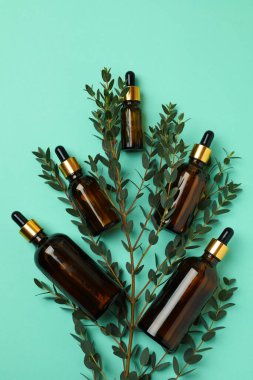 Kahverengi okaliptüs yağı şişeleri ve naneli arka planda dallar.