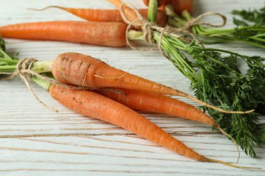 Beyaz ahşap masada ipli taze havuçlar.