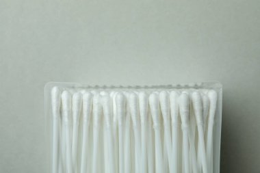 Açık gri zemin üzerinde pamuk çubukları olan plastik kutu