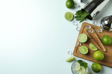 Bir bardak taze mojito kokteyli ve beyaz arka planda malzemeler.