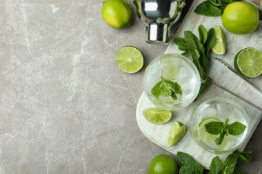 İçinde mojito kokteyli bardakları ve gri desenli masa malzemeleri olan bir tahta.